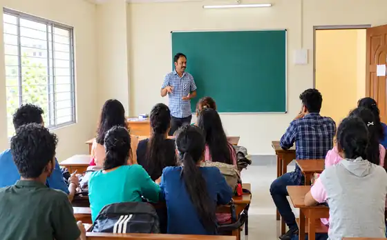 Dr. Subrata Mondal speaking with a classroom of students in front of a green board during an interactive session